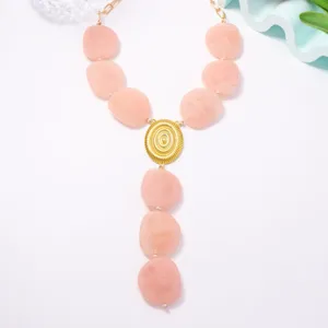 Primo piano dettagliato di una collana statement con perle rosa vintage e ciondolo dorato testurizzato.