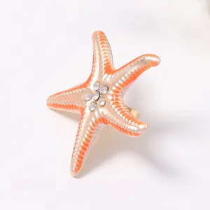 Close-up of the starfish ring detail, featuring gradient orange enamel and sparkling rhinestones.