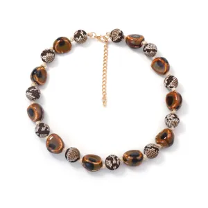 Primo piano dettagliato della collana di perle in ceramica irregolare con motivi serpente.