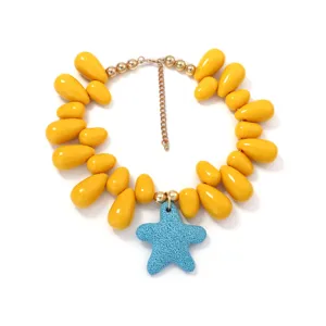 Close-up detail of the beach style yellow teardrop bead necklace with blue starfish pendant.