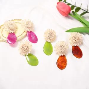 Bohemian raffia woven flower acrylic drop earrings detail view, niche designer vacation style.