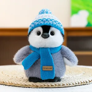Cute plush penguin toy with blue knitted hat and scarf, cozy winter desktop decor.