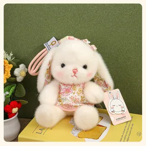 Gros plan détaillé du adorable pendentif lapin en peluche blanche avec robe florale.