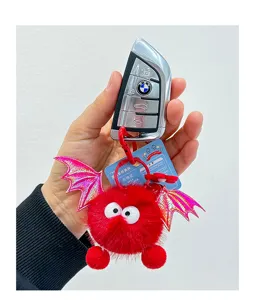 Cute plush bat doll keychain with fluffy red ball and shiny pink wings for car keys bag.