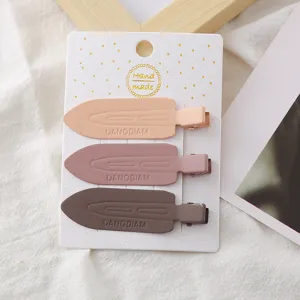 Gros plan de trois pinces à cheveux bec de canard en métal mat sur carte, style Y2K.