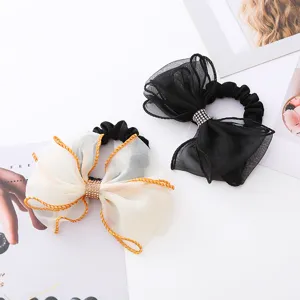 Élégant chouchou nœud en organza, vue détaillée du tissu transparent et des strass étincelants.