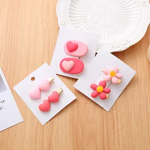 Vue détaillée de pinces à cheveux douces roses et rouges cœurs et fleurs sur cartes.
