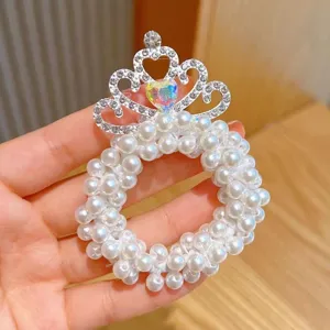 Close-up detail of a charming children pearl hair scrunchie with rhinestone crown decor.