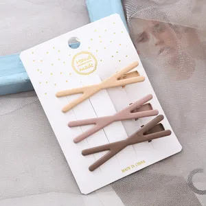 Gros plan détaillé de trois pinces à cheveux en métal colorées en forme de croix sur carte.