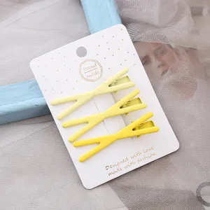 Ensemble de trois pinces à cheveux en métal jaune, jolies barrettes croisées sur carte blanche.