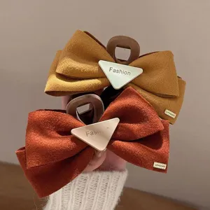 Gros plan sur la pince a cheveux noeud en velours vintage, texture suede et detail metallique.