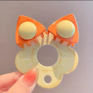 Detailopname van een oranje kattenoor haarclip, levendig y2k dopamine stijl accessoire.
