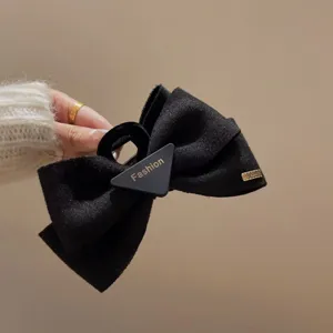 Élégante pince à cheveux nœud en velours noir avec détail de plaque triangulaire.