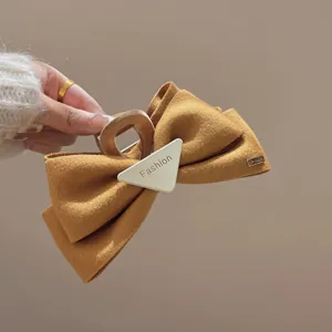 Vue de détail de la pince à cheveux noeud en feutre marron avec triangle et détail métal.