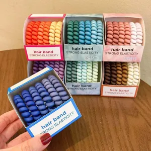 Detail view of gradient telephone cord hair bands in boxes, colorful spiral design for daily use.