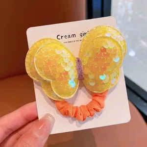 Gros plan détaillé d'un élastique cheveux nœud papillon à paillettes jaunes et tissu.
