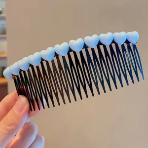 Close-up detail of cute white heart hair comb, black plastic teeth for styling bangs securely.