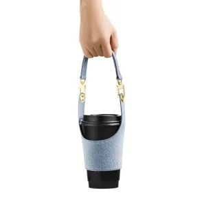 Portable denim coffee cup sleeve detail, detachable leather handle and secure gold metal hardware.