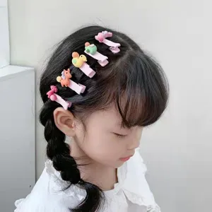 Dettaglio di fermaglio per capelli con simpatici animali in resina su clip rosa.