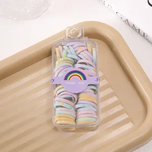 Detailed view of colorful elastic hair ties in a clear storage box with a rainbow wrapper.