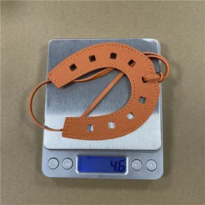 Detailansicht des orangefarbenen Leder-Hufeisen-Taschenanhängers mit feiner Doppelnaht.
