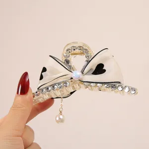 Elegant bow hair claw clip with sparkling rhinestones and pearl pendant for women styling.