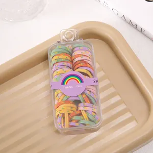 Colorful elastic hair ties for kids in a clear storage box with cute rainbow packaging.