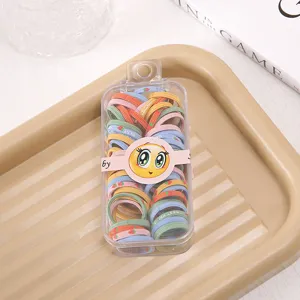 Detailed shot of colorful elastic hair bands for kids in a clear storage case with a cute smiley face.