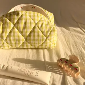 Nahaufnahme der gelben karierten Baumwoll-Kosmetiktasche mit weicher Steppung und Kirschfutter.