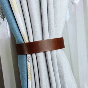 Detail shot of a minimalist brown PU leather curtain tieback holding modern curtains securely.
