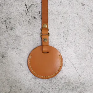 Detail view of brown PU leather round key case with metal hardware and strap for daily use.