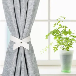 Detail view of a modern white PU leather curtain tieback on a textured gray curtain.