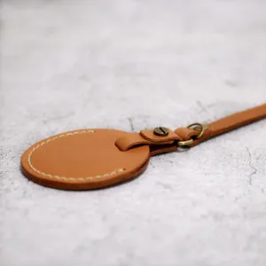 Brown PU leather round key tag detail view with metal screw fastener and stitching.