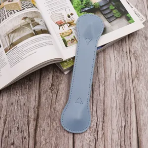Close-up of light blue leather weighted bookmark detail on wooden desk with magazine prop.