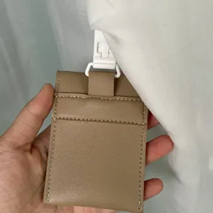 Portable pacifier pouch detail view, compact leather storage bag with white clip.