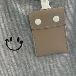 Baby storage bag detail shot, grey waffle fabric with cute smiley embroidery and brown pouch.