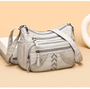 Detailed view of soft leather women crossbody bag with multi compartments, rivets, and shoulder strap.
