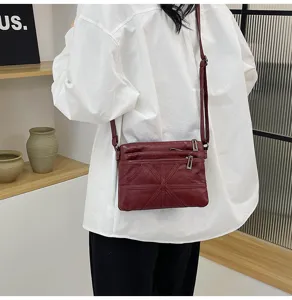 Soft leather crossbody shoulder bag detail view showing multi-pocket design and strap.