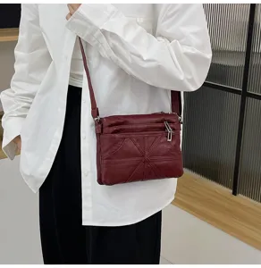 Wine red soft leather crossbody bag detail showcasing multi-pocket and sleek zipper design.