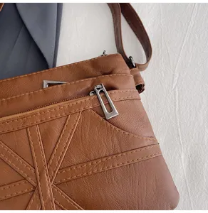 Close-up detail of a brown washed soft leather women crossbody bag with zip pocket and stitching.