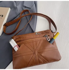 Detail view of the brown soft leather crossbody bag featuring multi-pocket zippers and strap.
