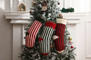 Tre splendide calze di Natale in maglia a righe appese a un albero innevato a festa.