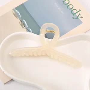 Close-up of translucent acrylic hair claw clip with cross design on white tray detail view.