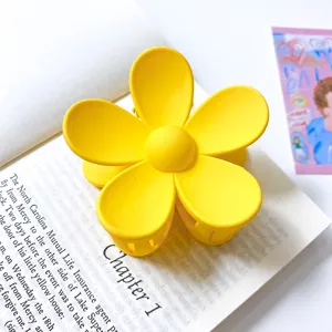 Gros plan détaillé d'une pince à cheveux jaune vif en forme de fleur avec texture mate.