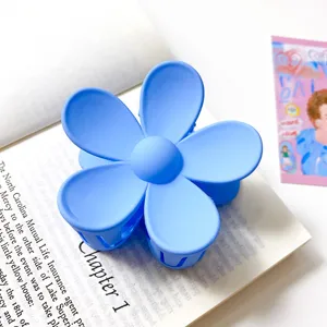 Gros plan détaillé d'une pince à cheveux fleurie bleue mate sur un livre ouvert.