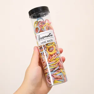 Detail view of colorful small hair bands packed in a clear cylinder for daily styling.