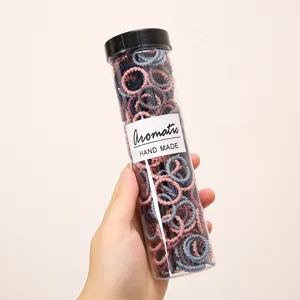 Close-up detail of colorful small hair ties in a clear storage tube for daily kids styling.