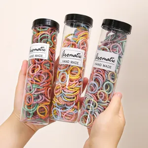 Colorful small hair ties for kids, stretchy rubber bands in clear cylinders, hair accessories.