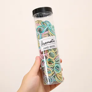 Colorful elastic small hair ties for kids, stretchy rubber bands inside clear storage jar.