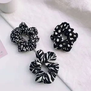 Set of 3 black and white fabric hair scrunchies with leopard, dot and zebra prints.